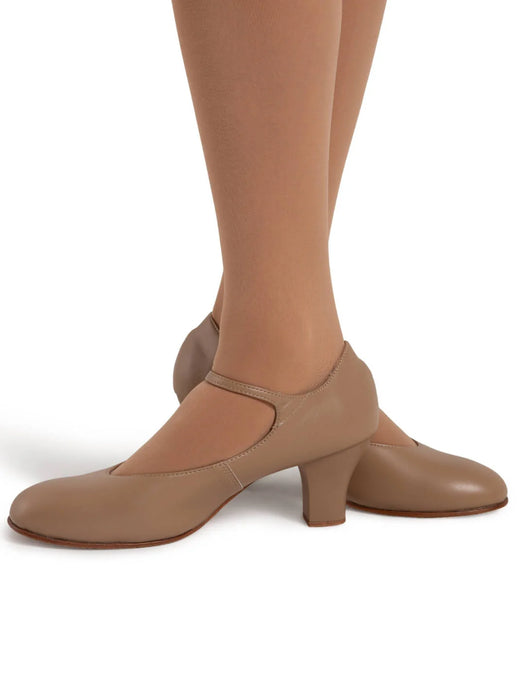 Tan high-heeled shoes worn with brown tights on a white background