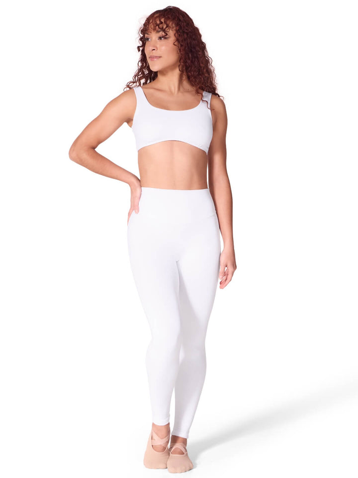 Woman wearing a white sports bra and leggings on a white background