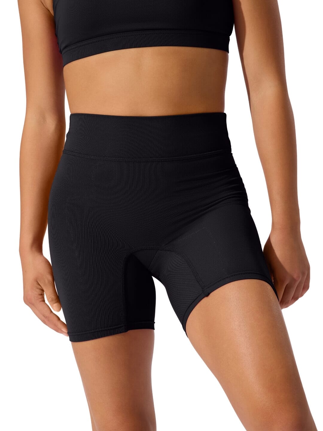 Person wearing black athletic shorts and sports bra on a white background