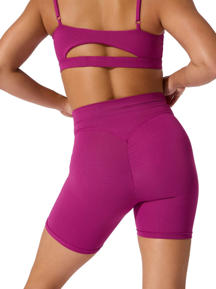 Person wearing a purple sports bra and shorts set on a white background