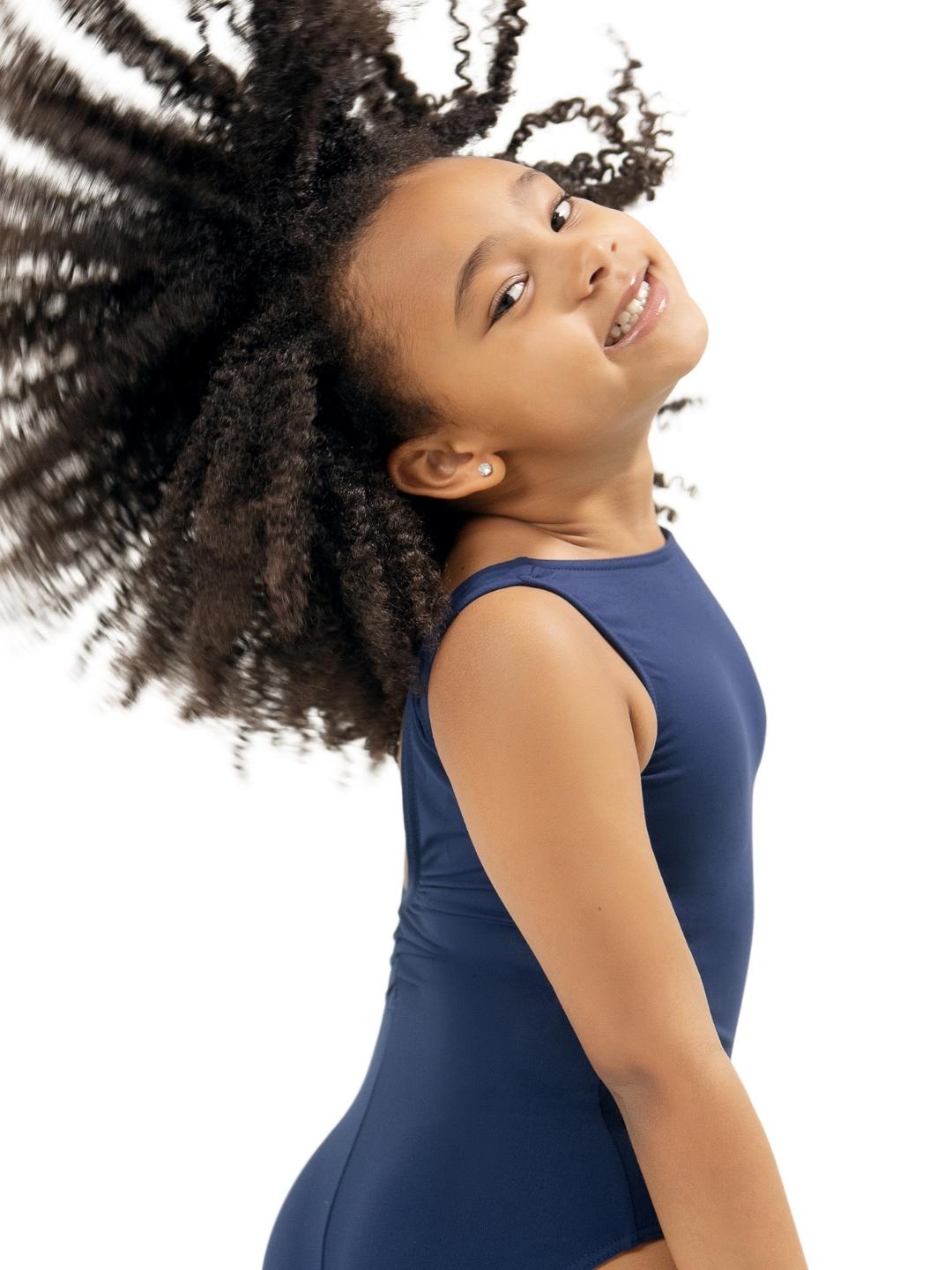 Young girl with voluminous hair wearing a blue dress against a white background