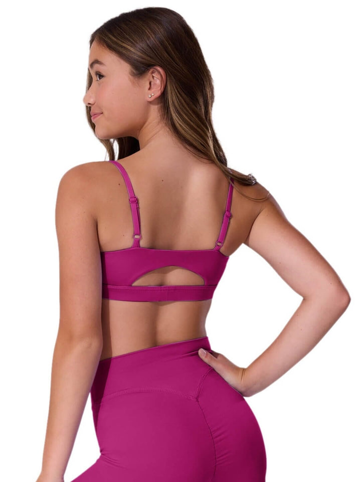 Woman wearing a bright pink sports bra and leggings on a white background