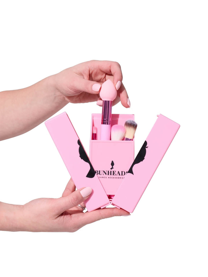 Pink makeup brush set with 'Bunhead' branding held by a hand against a white background
