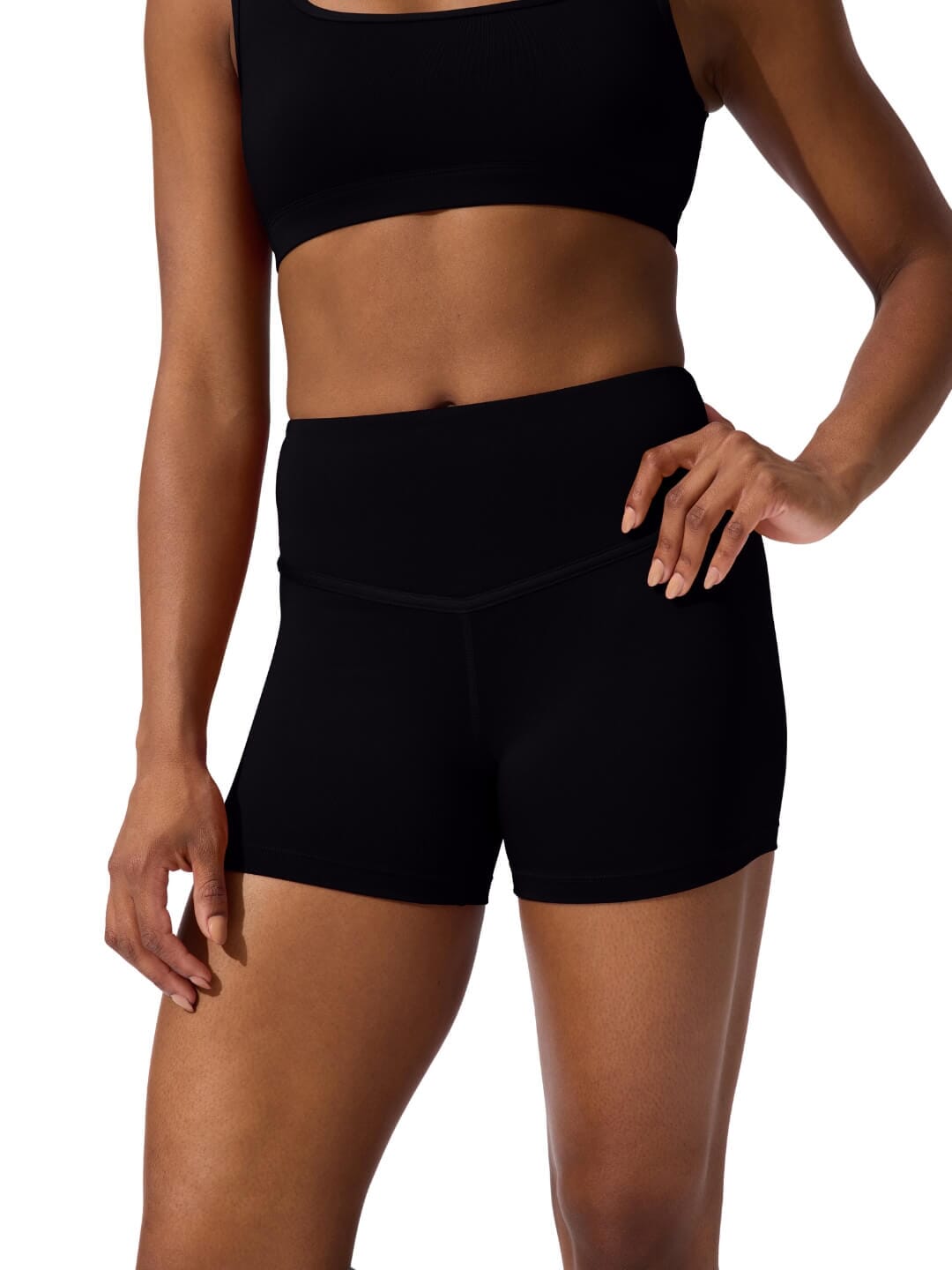 Person wearing black athletic shorts and sports bra on a white background