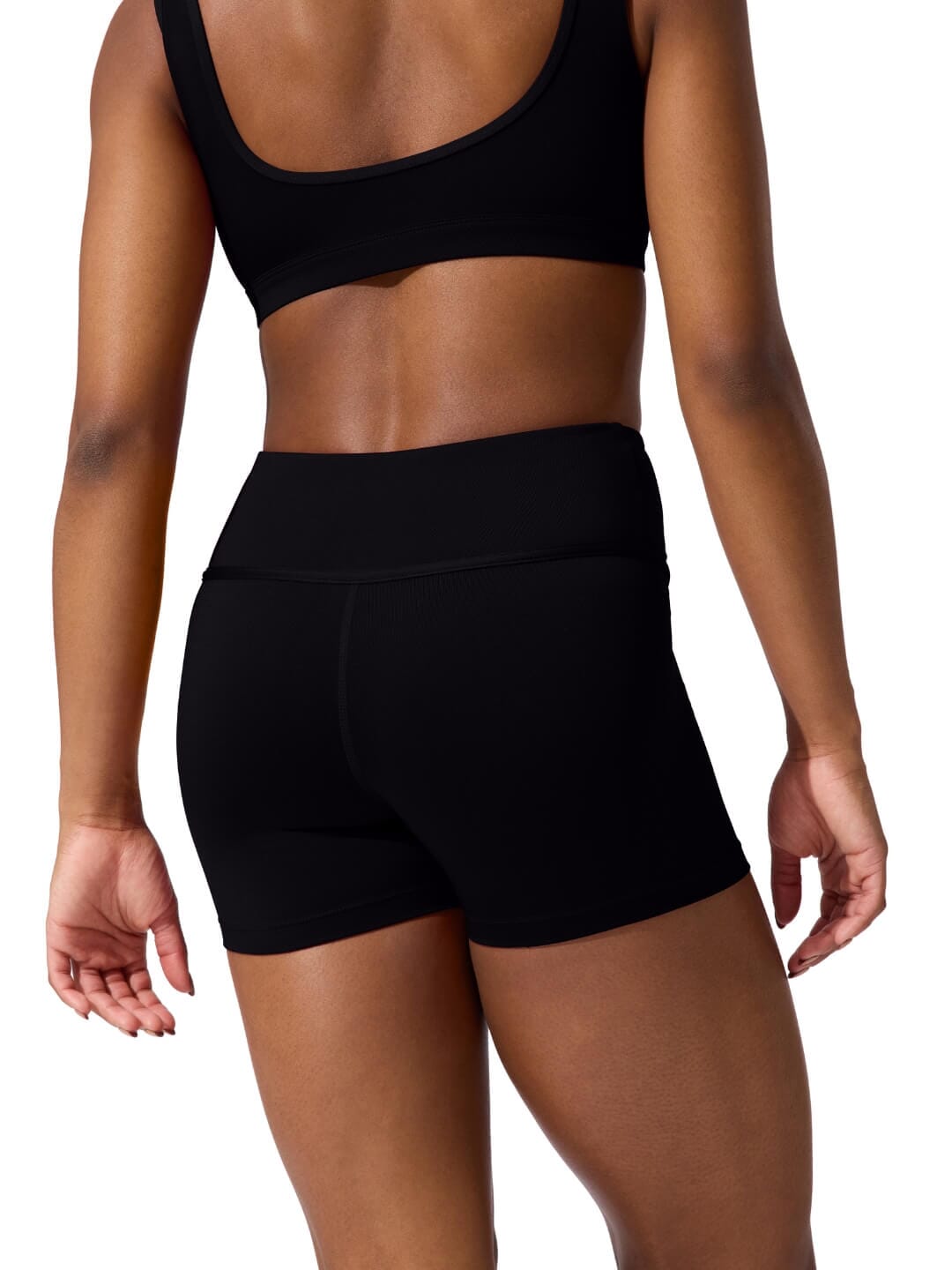 Person wearing black athletic shorts and sports bra on a white background