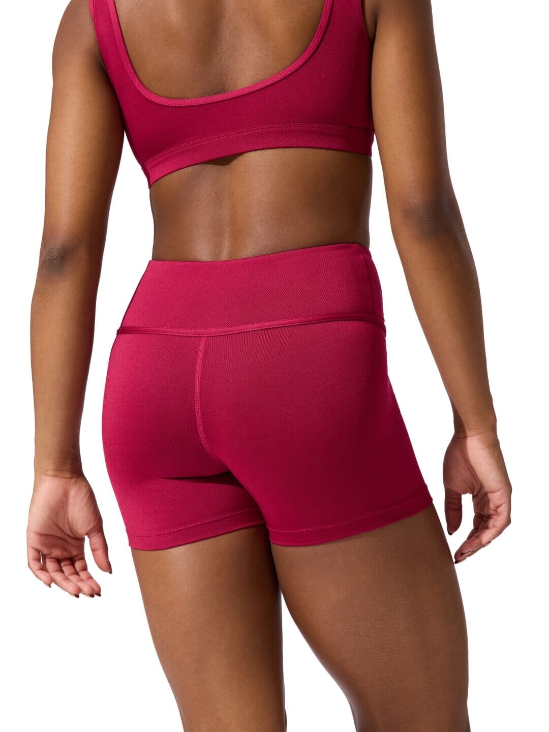 Person wearing a red sports bra and shorts on a white background