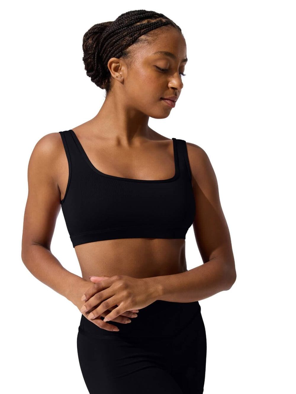 Woman wearing a black sports bra and leggings on a white background