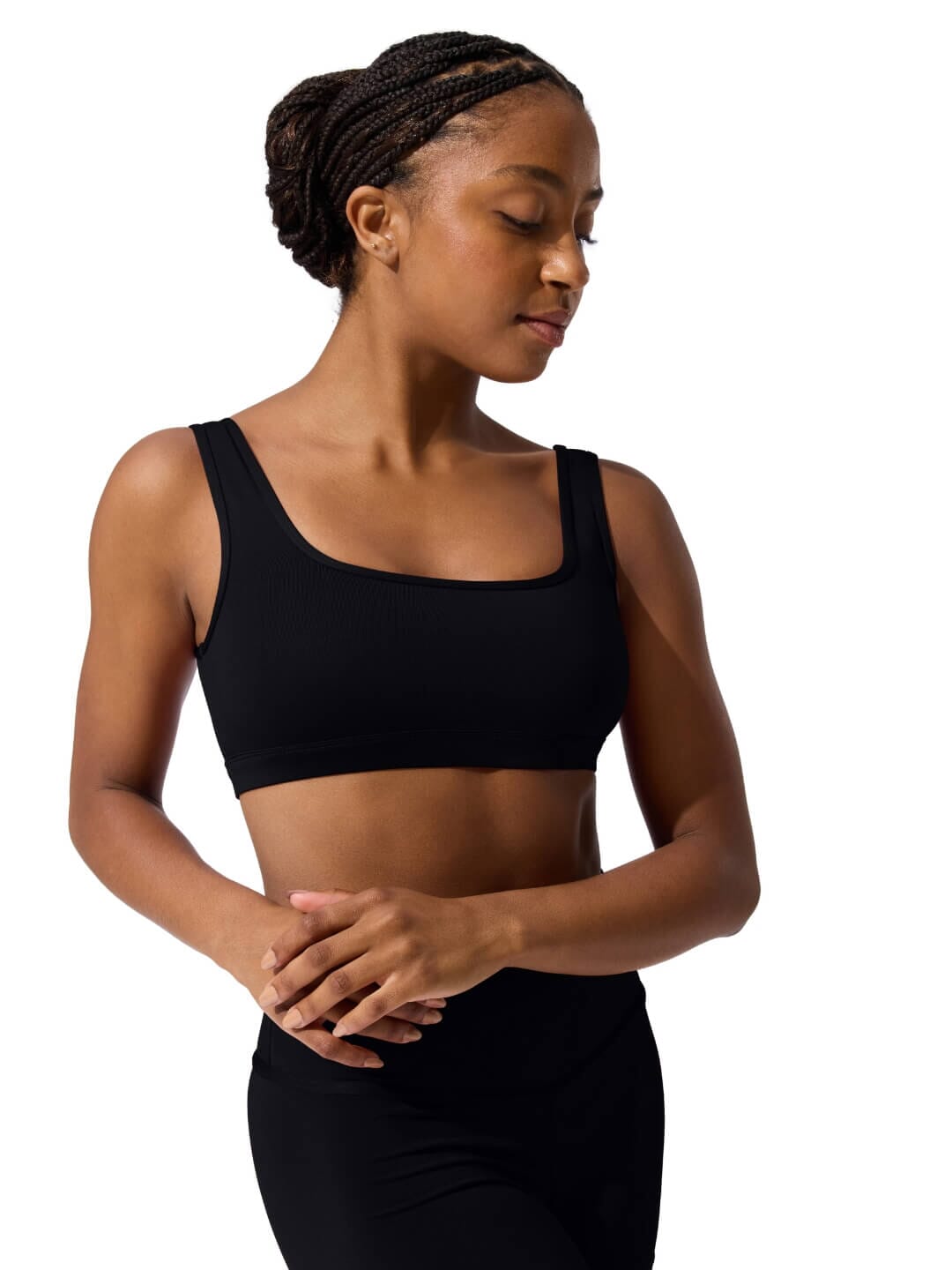 Woman wearing a black sports bra and leggings on a white background
