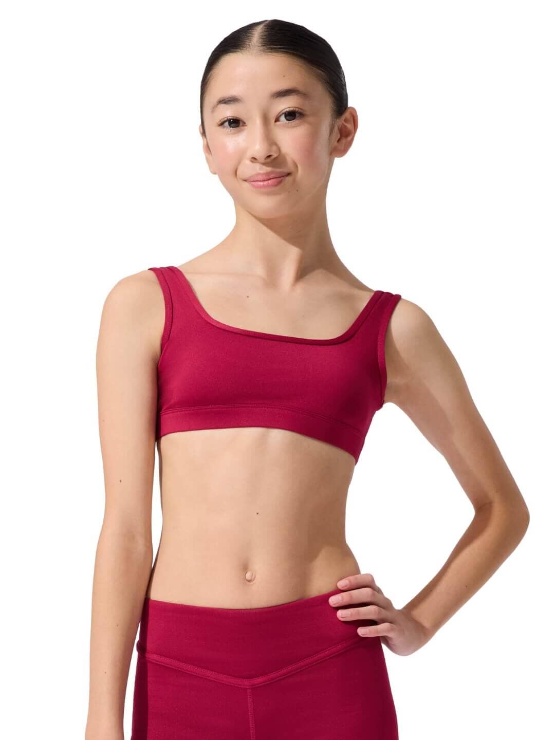 Woman wearing a red sports bra and leggings on a white background