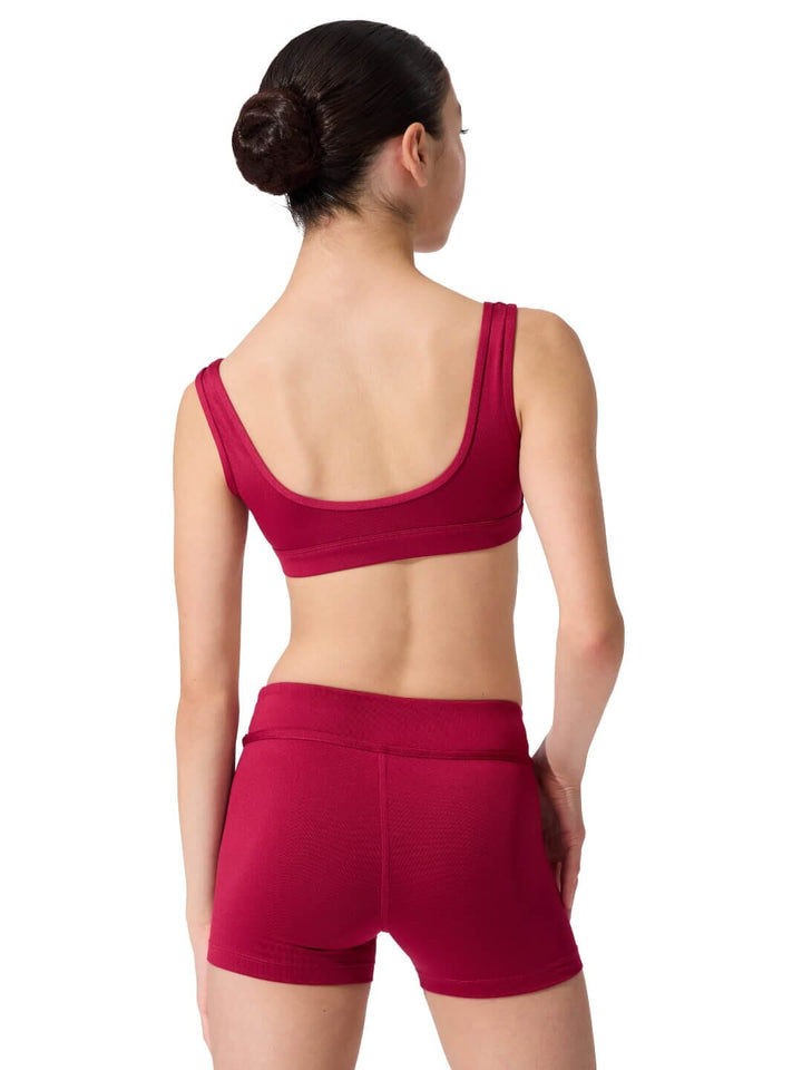 Woman wearing a red sports bra and shorts on a white background