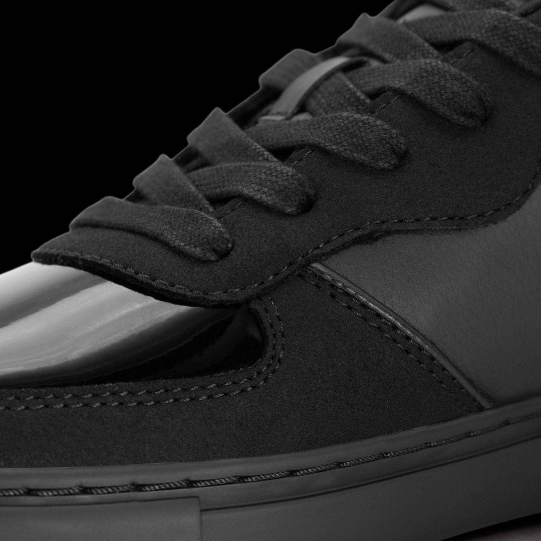 Close-up of a black sneaker with white sole on a black background