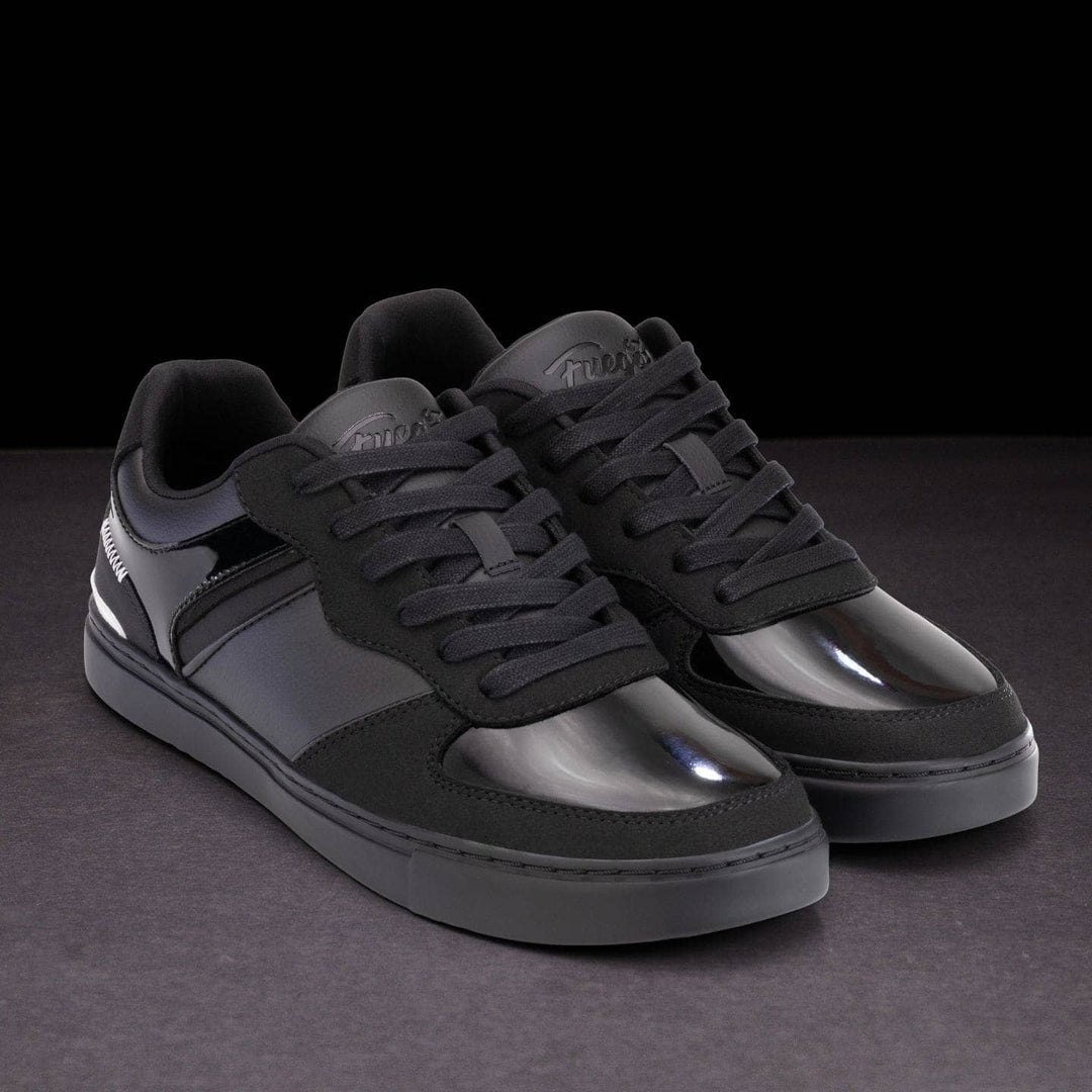 Black sneakers with reflective soles on a dark background