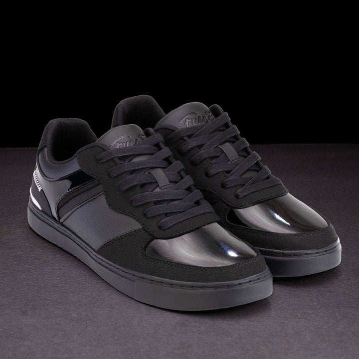 Black sneakers with reflective soles on a dark background