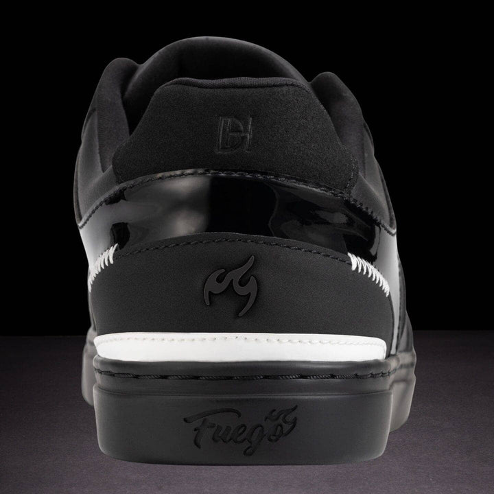 Black sneaker with white sole on a dark background