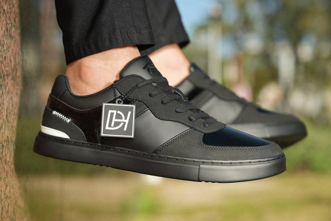 Black sneakers with a brand logo worn outdoors on a blurred background