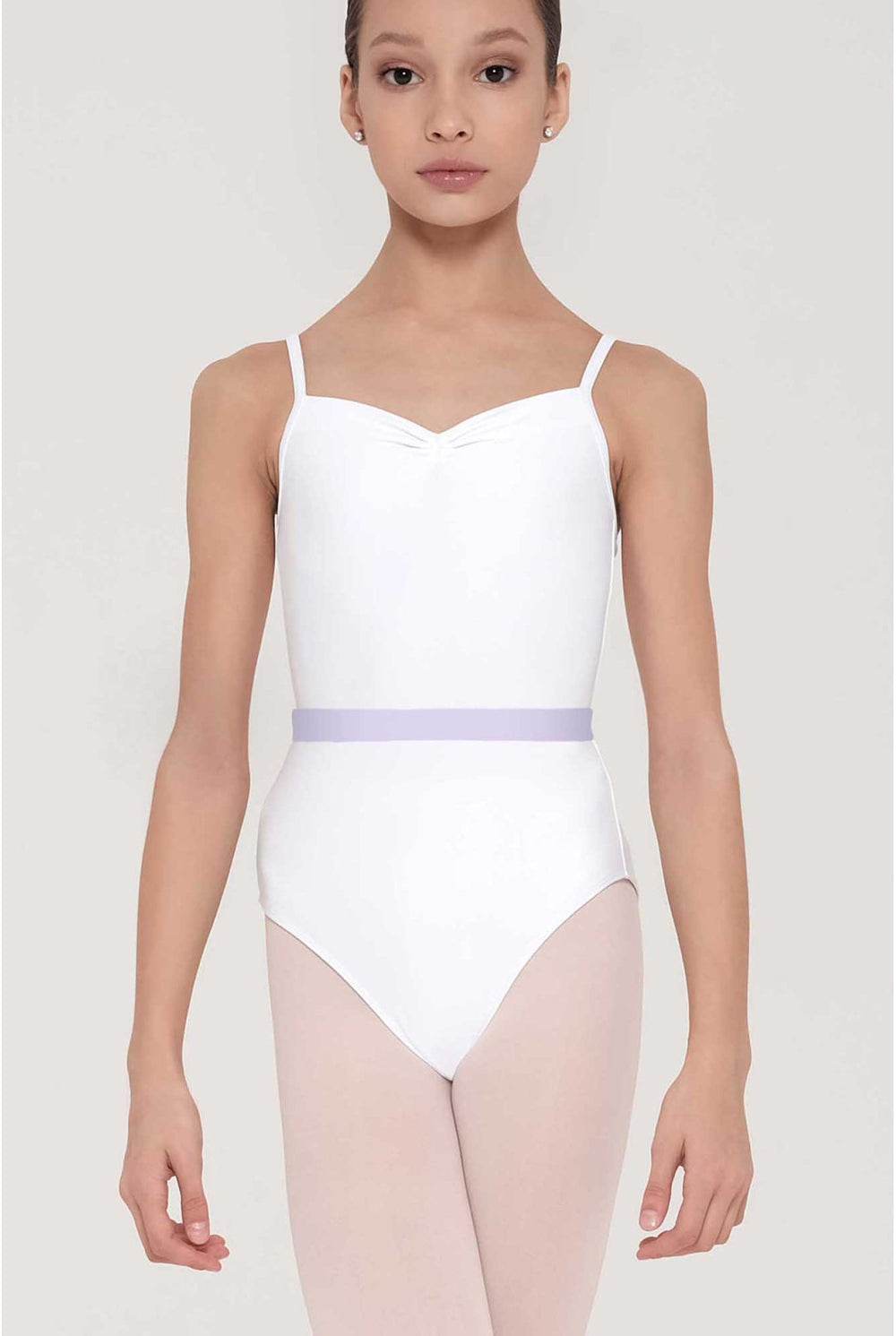 A young girl modeling a white ballet leotard with thin shoulder straps and a light lavender waistband, paired with light pink tights, against a solid light gray background.