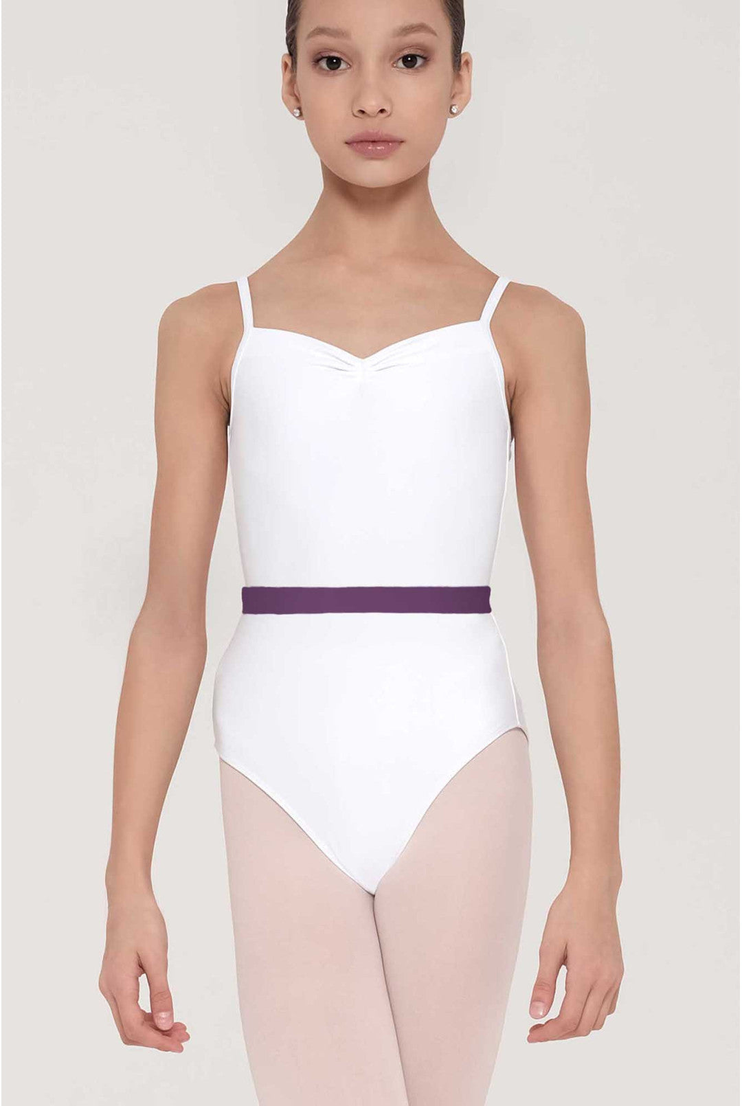 A young girl modeling a white ballet leotard with thin shoulder straps, a sweetheart neckline, and a thin purple waistband, paired with light pink tights against a light gray studio background.