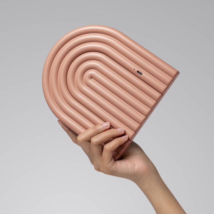 Hand holding a pink inflatable pool noodle against a gray background
