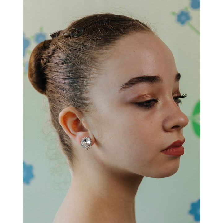 Close-up of a person wearing a silver earring with a floral background