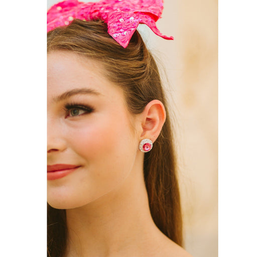 Close-up of a woman wearing pink earrings and a matching headband with sequins.