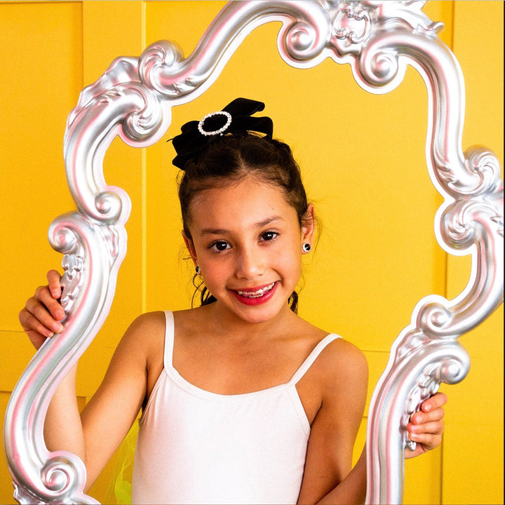 Young girl holding a decorative mirror against a yellow background