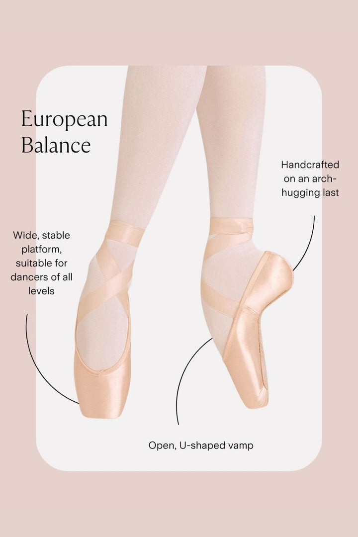 A pair of pale pink ballet pointe shoes worn on a dancer's feet, shown with callout lines and text explaining features like European balance, wide stable platform, handcrafted arch, and open U-shaped vamp on a soft beige background.