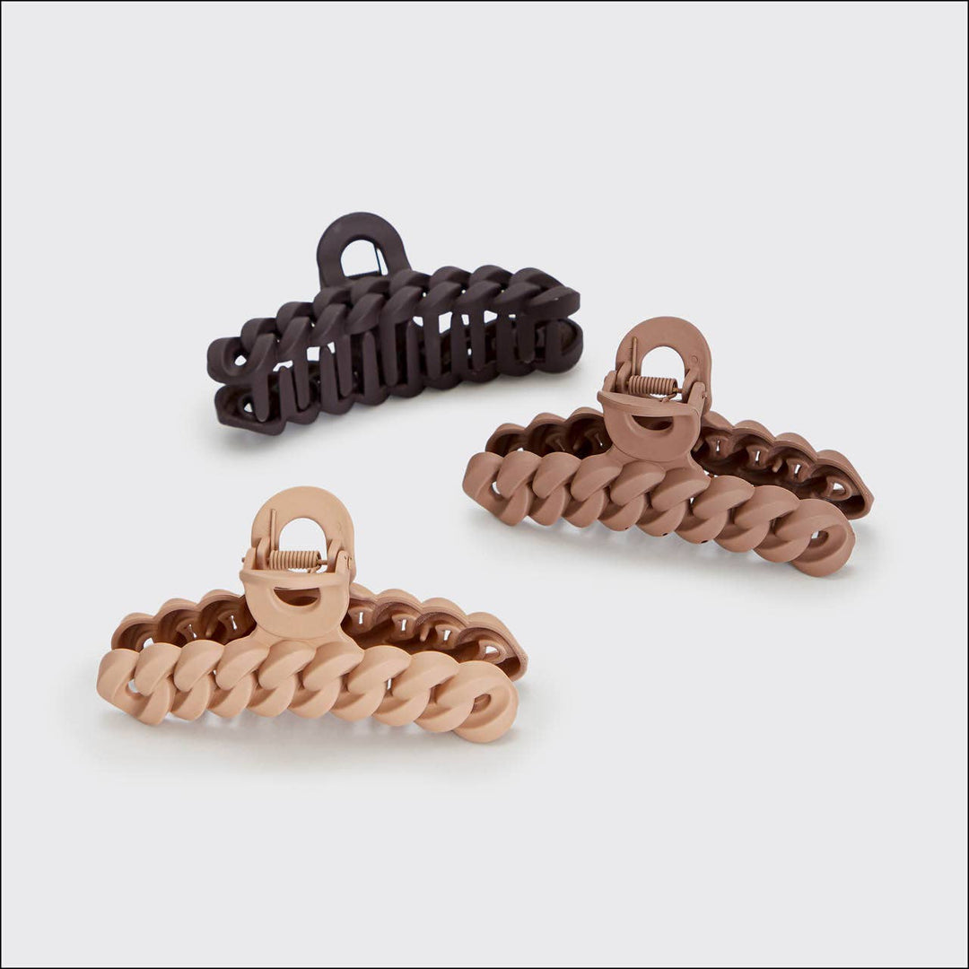 Three hair clips in black, brown, and rose gold on a light gray background