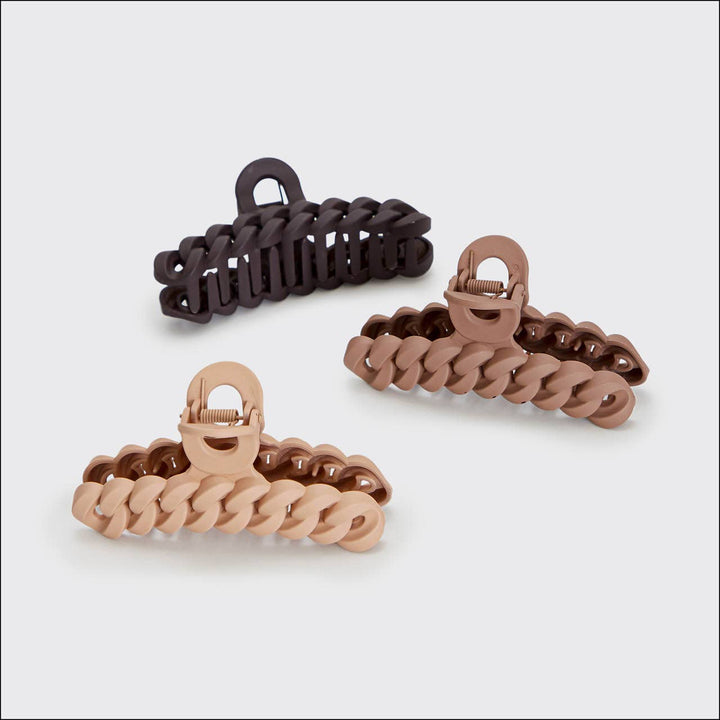 Three hair clips in black, brown, and rose gold on a light gray background