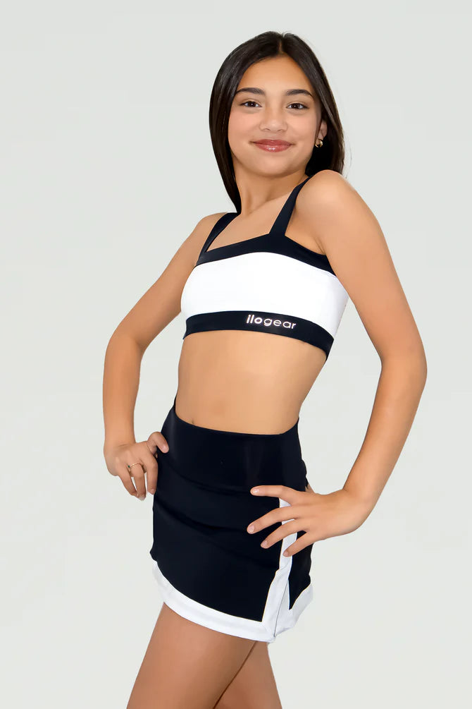 Woman wearing a black and white sports bra and shorts set on a plain background