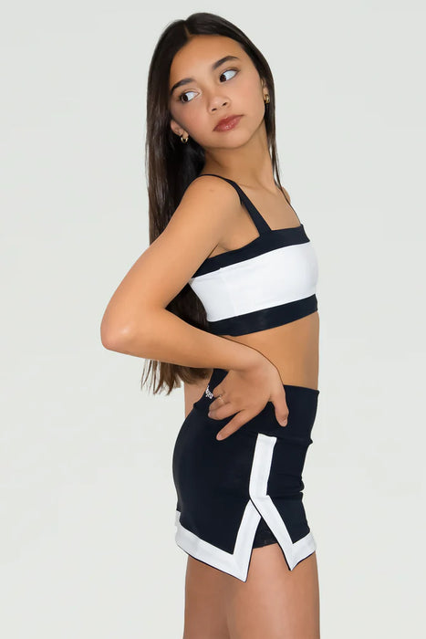 Woman wearing a black and white sports bra and shorts set on a plain background