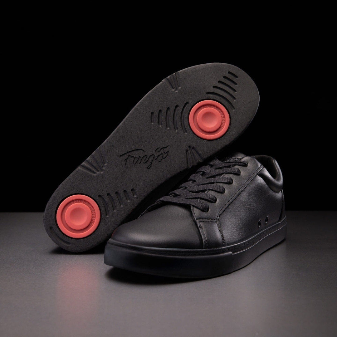A pair of black dance sneakers with red pivot points on the soles, placed side by side on a dark background.