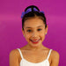 Young girl with a purple hair bow and white tank top against a purple background