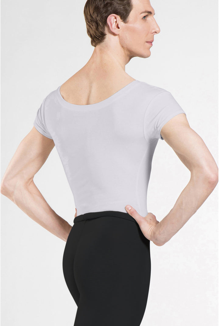 A male model shown from the back wearing a light gray short-sleeve leotard and black dance pants against a plain light gray studio background.