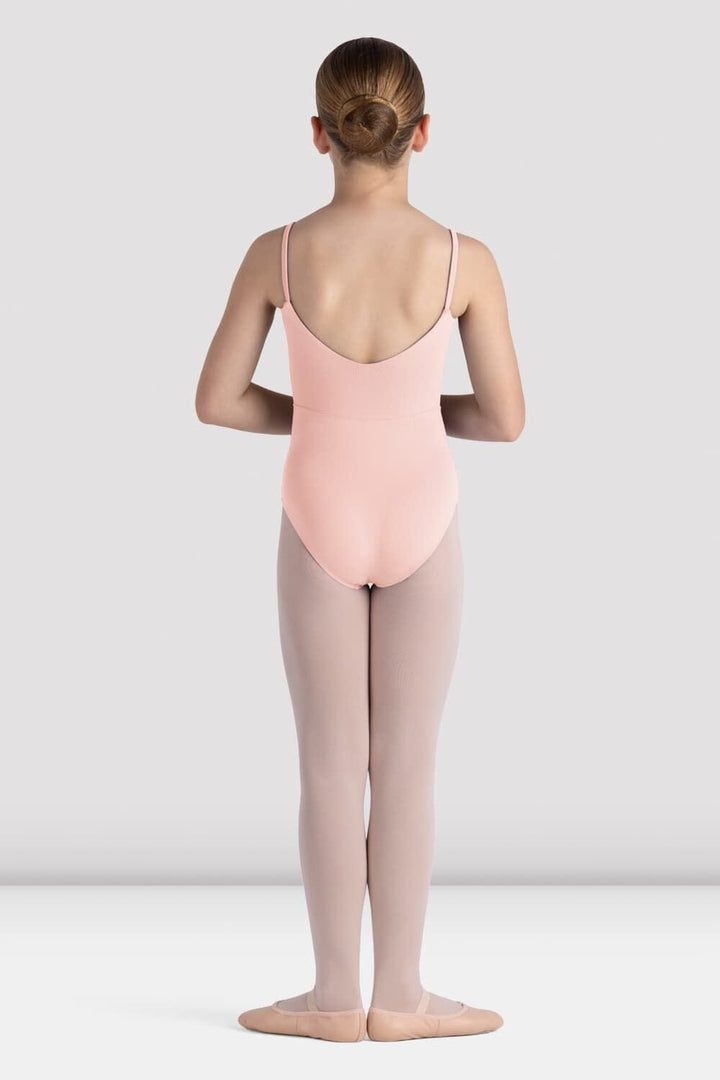 Ballerina in a pink leotard and gray tights standing against a white background