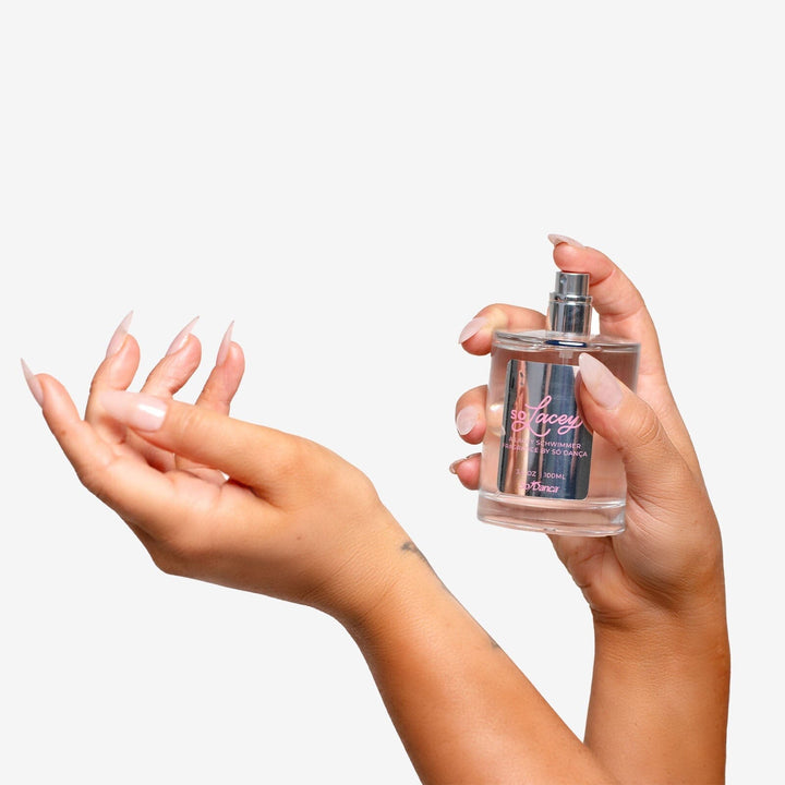 Person holding a perfume bottle with a plain background