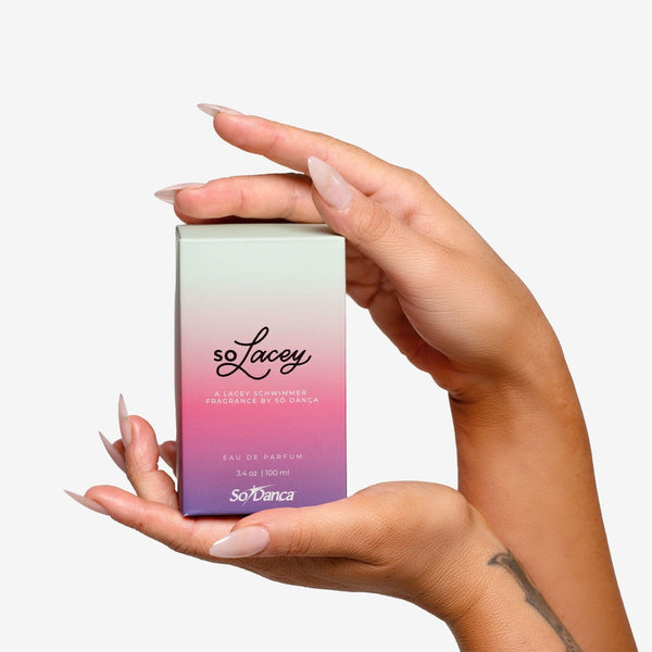 Hand holding a gradient-colored 'soLacey' perfume box against a white background