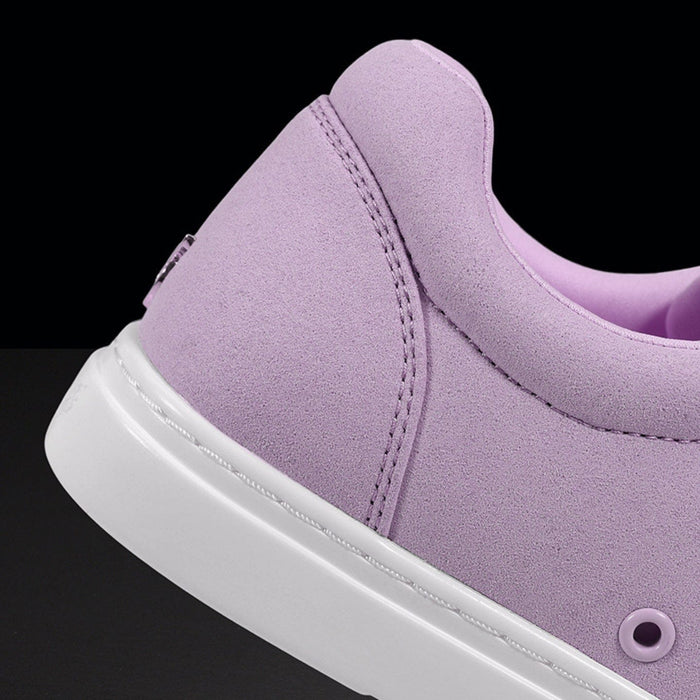 Close-up of a purple sneaker with a white sole on a black background