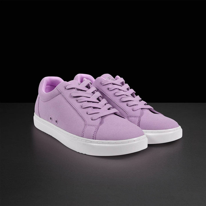 Pair of purple sneakers with white soles on a black background