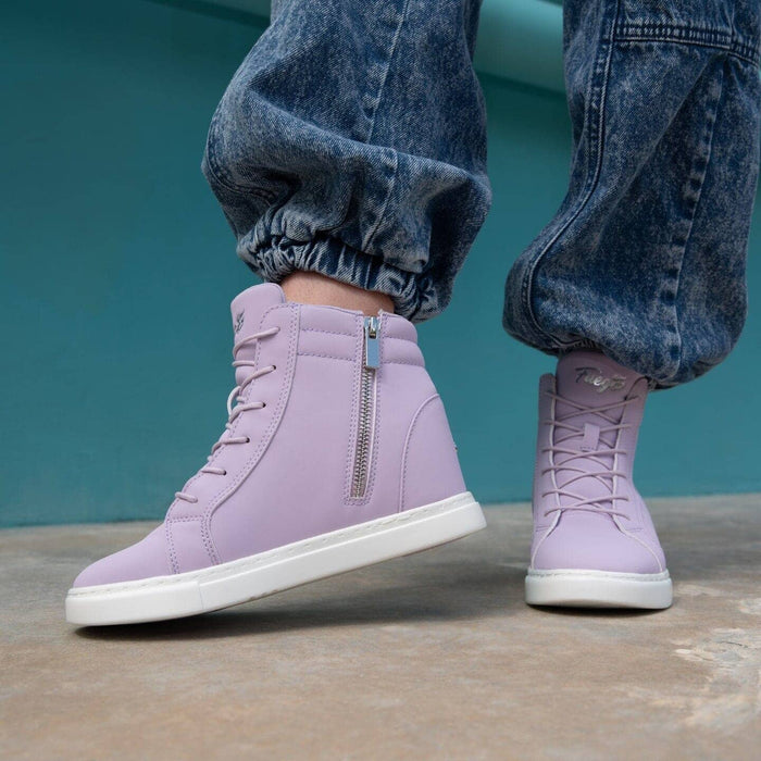 Purple high-top sneakers with white soles worn with blue jeans against a teal background