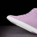 Purple sneaker with white sole on a black background