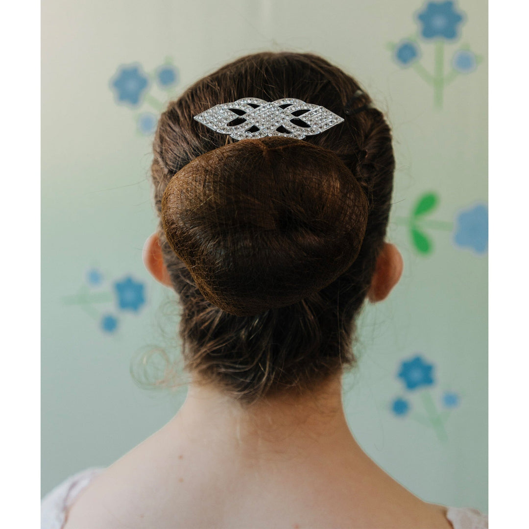 Person with a decorative hair clip in their bun against a floral-patterned background