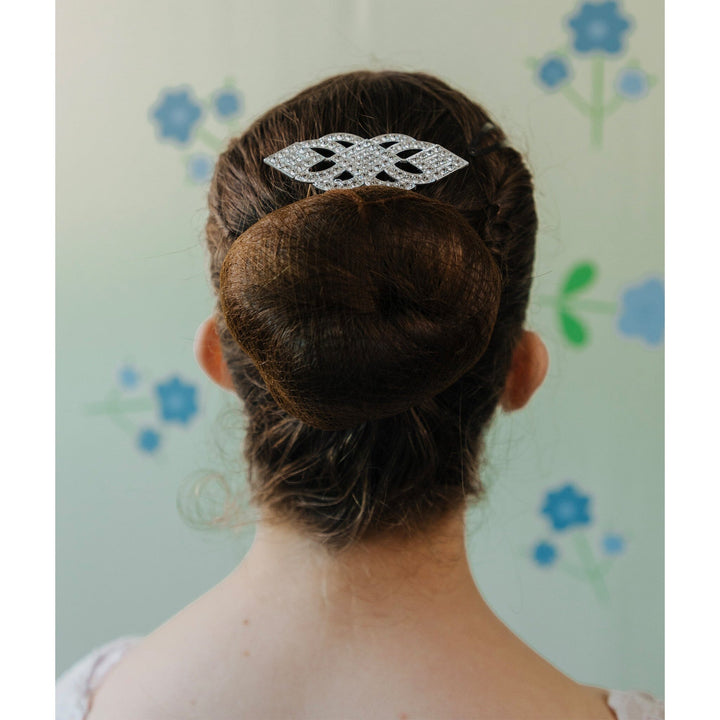 Person with a decorative hair clip in their bun against a floral-patterned background