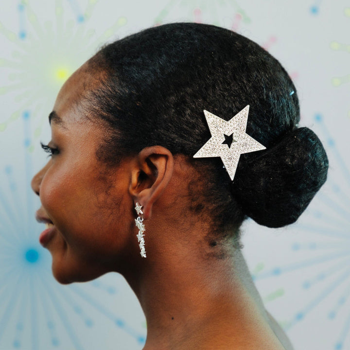 Woman with a star-shaped hair accessory and earrings against a colorful abstract background