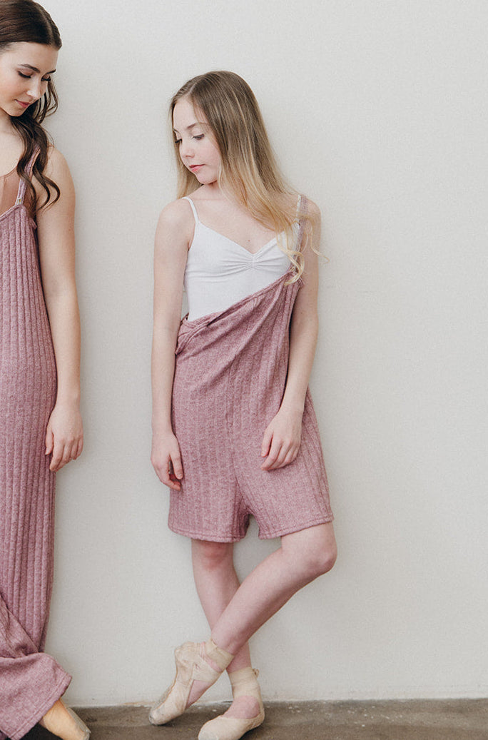 Dancer against a white wall in a Pink color romper.