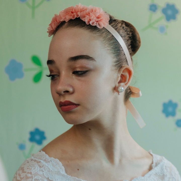 Woman wearing a pink floral headband against a floral-patterned background