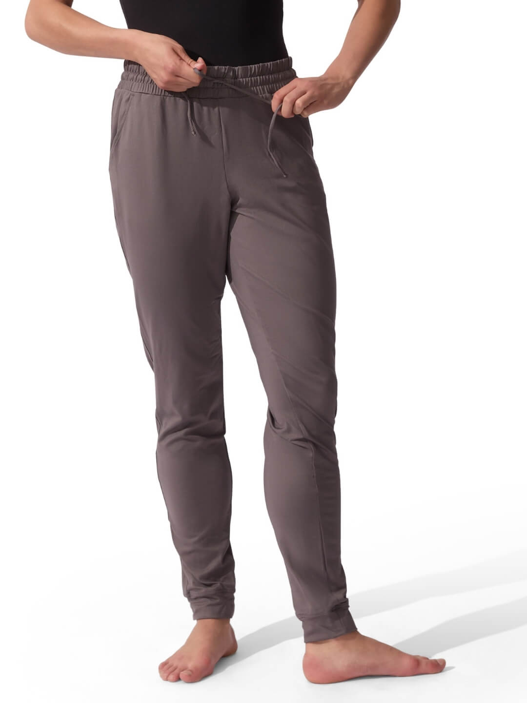 Person wearing brown jogger pants on a white background
