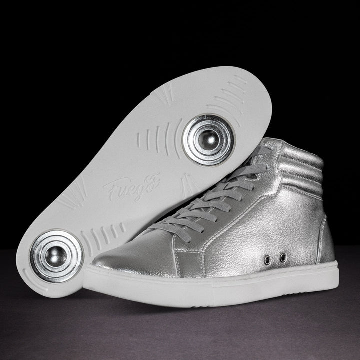 A pair of high-top dance sneakers with silver upper and white sole, showcasing the side profile of the shoe with the sole visible, highlighting the flame design on the side.